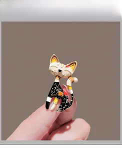 Detail of artistic enamel cat brooch with floral patterns held to show scale