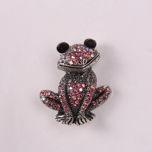Close-up of vintage silver frog brooch with pink rhinestones and black gem eyes