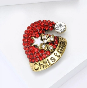 Vue macro de la broche bonnet de Noël avec strass rouges et gravure festive