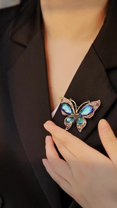 Close-up of luxury vintage butterfly brooch with blue crystals on a black suit jacket