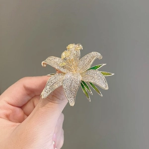 Luxury lily brooch with sparkling crystals, yellow gemstones and green enamel leaves