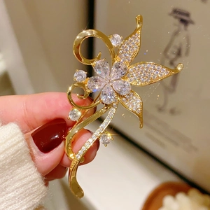 Close-up of a vintage golden bauhinia flower brooch with sparkling white zircons
