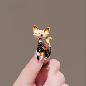 Macro shot of an elegant black enamel cat brooch with floral details held by a hand