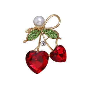 Détail d'une broche cerise avec cristaux de cœur rouges, pierres vertes et perle