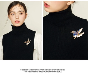 Détail d'une broche colibri en cristal avec émail bleu sur un pull noir élégant