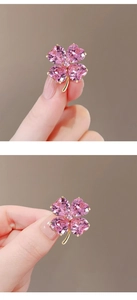 Détail d'une broche trèfle rose avec cristaux en forme de cœur et griffes en métal doré