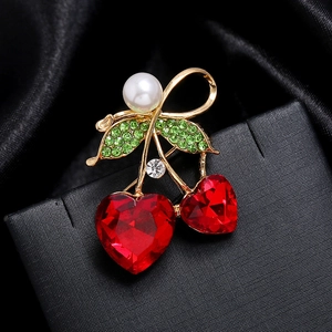 Détail de la broche cerise avec cristaux cœur rouges, feuilles vertes et perle blanche