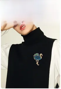 Broche flamant élégante avec cristaux bleus sur un vêtement en maille noire