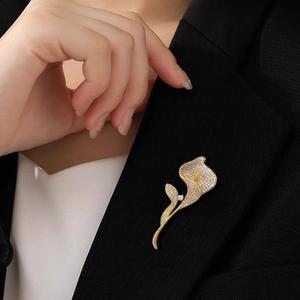 Elegante spilla a forma di calla dorata con cristalli su un bavero di abito nero