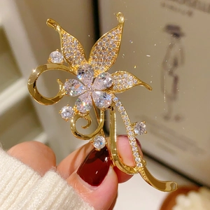 Macro shot of elegant golden bauhinia brooch with pavé cubic zirconia on a white sweater