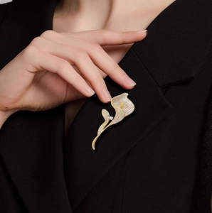 Elegante spilla calla in oro con diamanti scintillanti su risvolto di giacca nera
