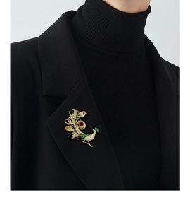 Vue détaillée d'une broche paon de luxe aux cristaux colorés sur une veste noire
