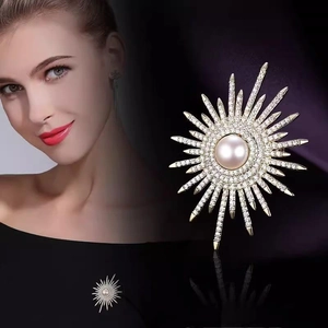 Dettaglio della spilla a fiore solare con perla rosa centrale e raggi di cristallo
