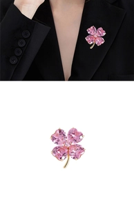 Détail d'une broche trèfle à quatre feuilles rose avec cristaux en cœur et monture dorée