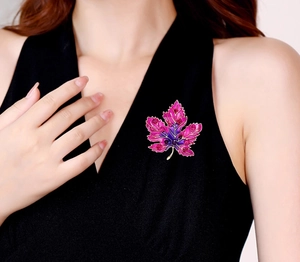 Detail of maple leaf brooch with pink gradient enamel and red crystals on black suit