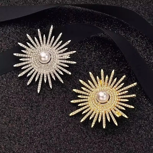 Dettaglio di spille a girasole in argento e oro con cristalli lucenti e perle bianche