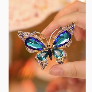 Elegant butterfly brooch featuring aurora purple crystals and light blue gemstones on gold metal