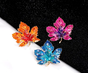 Detailed close-up of three maple leaf brooches with gradient enamel and crystals