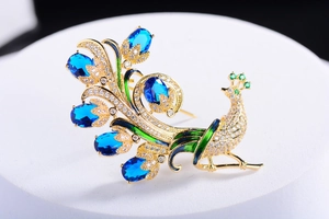 Gros plan détaillé d'une broche paon avec pierres bleu roi et finition en émail vert