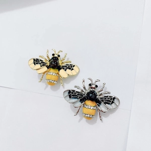 Gedetailleerde macro van gouden en zilveren bijenspelden met email en fonkelende kristallen