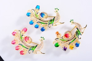 Vue détaillée de trois broches paon de luxe en bleu rose et multicouleur avec cristaux