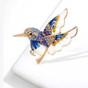 Broche colibri exquise avec cristaux bleus et émail incrusté sur une base dorée