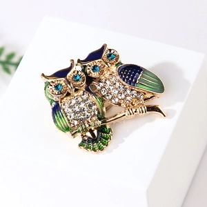 Close-up of owl brooch with blue enamel and rhinestones on a minimalist background