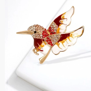 Élégante broche colibri avec strass colorés et émail sur un podium blanc raffiné