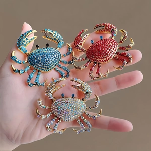 Vue macro détaillée de trois broches crabe ornées de cristaux en bleu, rouge et multicolore