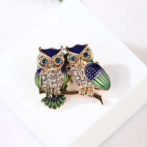 Detailed close-up of blue enamel owl brooch with sparkling rhinestones on golden branch