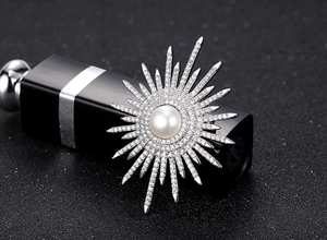 Dettaglio di una spilla a sole in argento con perla centrale e scintillanti zirconi