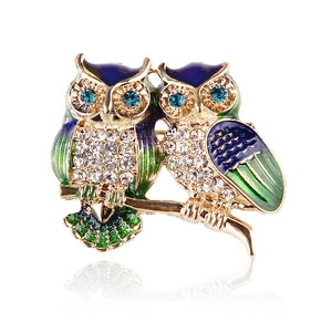 Detailed close-up of owl brooch with blue enamel wings and sparkling rhinestones