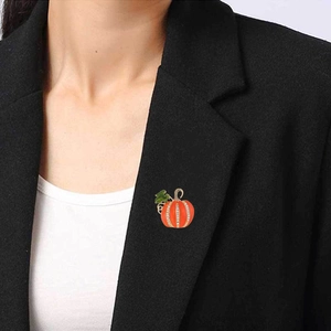 Détail d'une broche citrouille étincelante en émail orange et strass sur un blazer noir