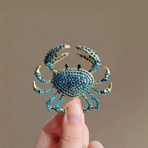 Gros plan détaillé d'une broche crabe avec strass bleus et finition en métal doré
