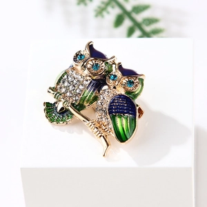 Exquisite owl duo brooch featuring blue enamel and sparkling rhinestones on golden branches