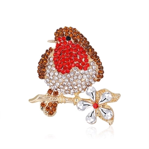 Detailed macro view of gold-tone bird brooch with red and brown pavé crystal rhinestones
