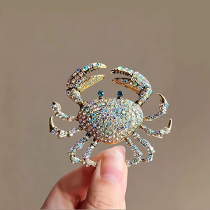 Vue détaillée de la broche crabe dorée ornée de strass AB étincelants et d'yeux bleus