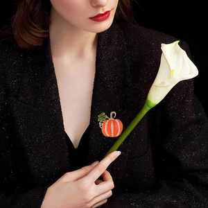 Détail d'une broche citrouille en émail orange brillant sur une veste en tweed noir