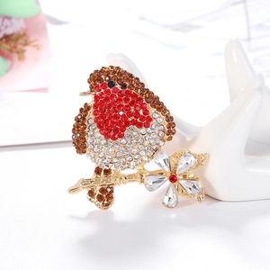 Detail of a gold bird brooch with red and brown crystals perched on a plum blossom branch