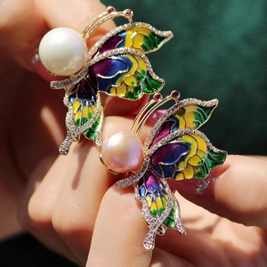 Gros plan de broches papillon en émail coloré avec grandes perles et cristaux micro-pave