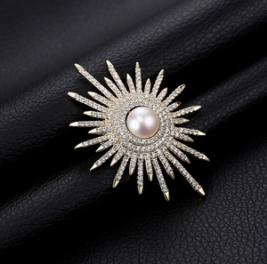 Spilla a raggiera elegante con perla centrale e cristalli scintillanti su base oro