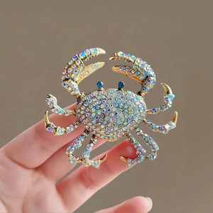 Détail d'une broche crabe dorée ornée de strass AB multicolores scintillants et yeux bleus