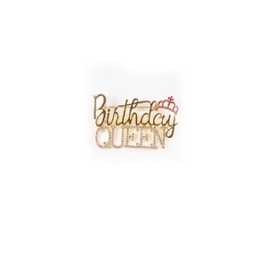 Close-up of a gold Birthday Queen brooch with sparkling crystals for birthday parties