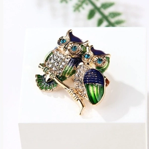 Exquisite owl brooch with gradient blue enamel and sparkling crystals on a white pedestal