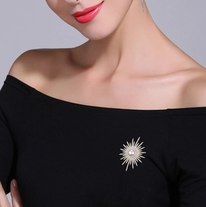 Dettaglio di spilla a girasole con perla e zirconi su un abito nero elegante