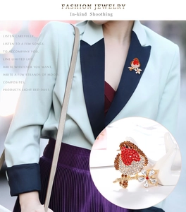 Detailed macro view of a crystal bird brooch with red rhinestones on a golden branch