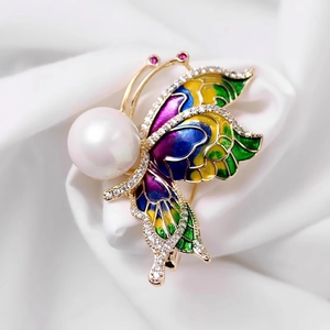 Gros plan d'une broche papillon avec ailes en émail coloré et perle blanche