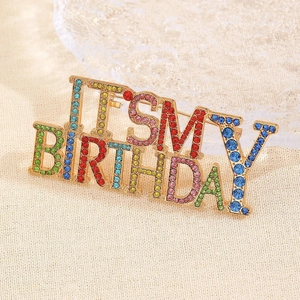 Détail de la broche 'IT'S MY BIRTHDAY' avec cristaux colorés sur socle en alliage doré