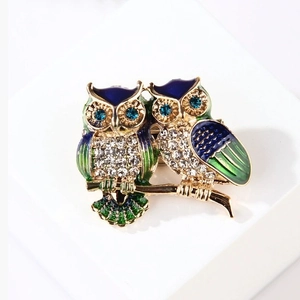 Chic double owl brooch with blue and green enamel and sparkling rhinestones on a gold base