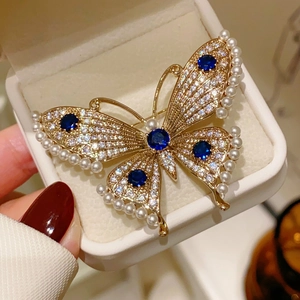 Detail of luxury butterfly brooch with blue gemstones, pearls and crystal rhinestones